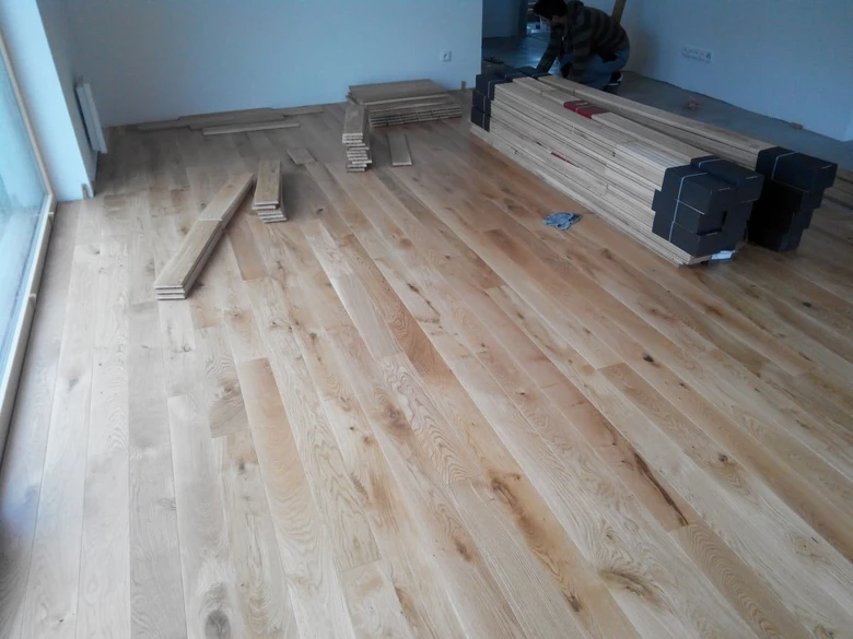 Instalace dřevěné podlahy v místnosti s pracovníkem.