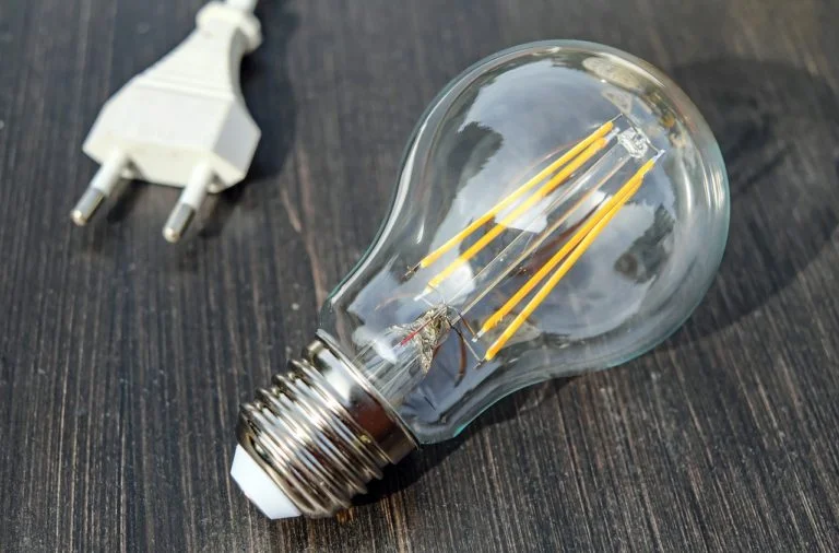 Průhledná žárovka s zapalovačem vedle elektrické zásuvky.