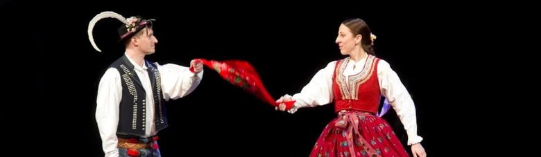 Muž v valašském kroji tančí s ženou při folkloru.