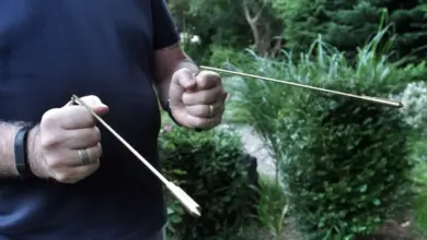 Muž drží dvě hůlky na hledání vody venku v zahradě.