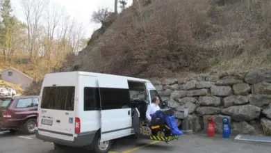 Bílý přístupový vůz na parkovacím místě pro invalidy s rozloženou rampou.