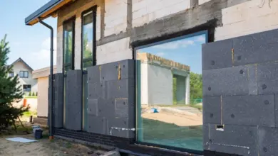 Stavba domu s izolačními deskami kolem oken pro tepelnou izolaci.