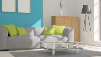 Modern obývací pokoj s tyrkysovou stěnou a zelenými polštáři.