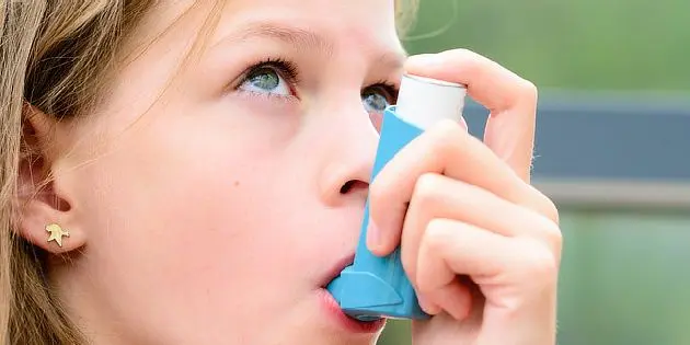 Dívka používá inhalátor pro léčbu astmatu.