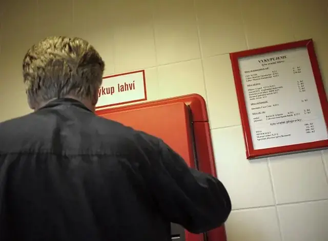 Muž vrací skleničku do automatu na výkup láhví.