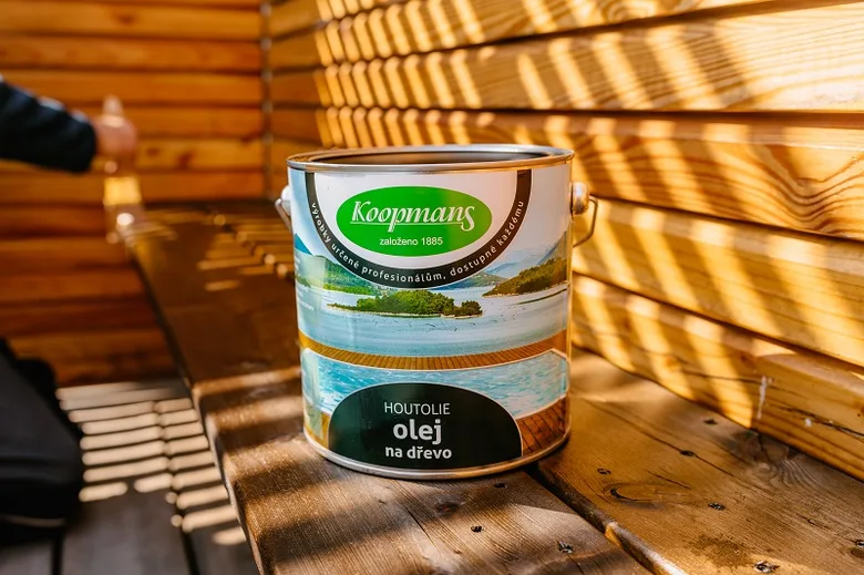 Kanárek oleje na dřevo stojí vedle dřevěné stěny.