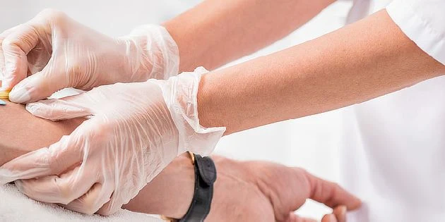 Zdravotník podává injekci pacientovi v rukavicích