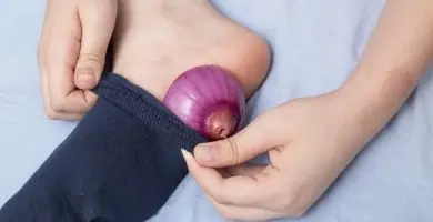 Cibule v modré ponožce na chodidle pro nachlazení.