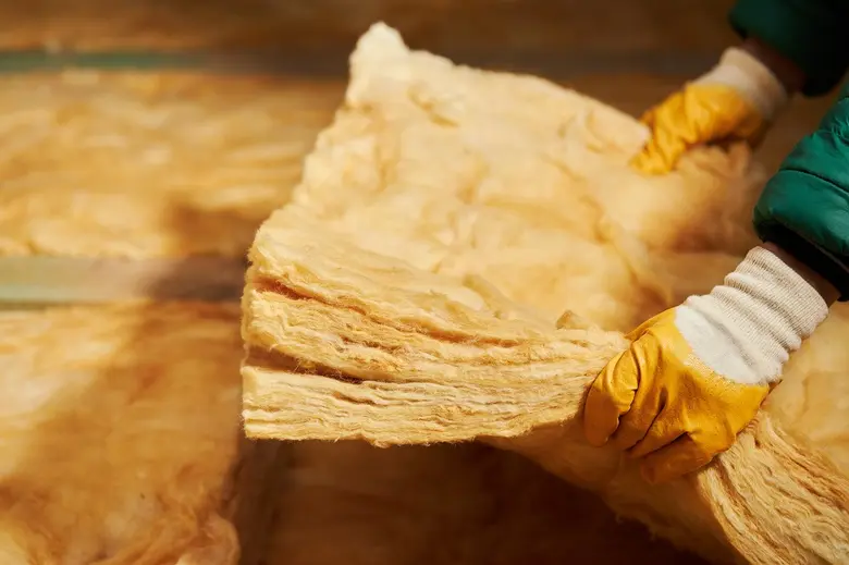 Pracovník drží desku tepelné izolace z minerální vlny.