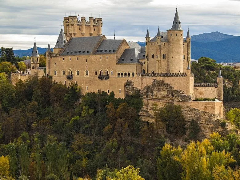 Hrad Alcázar v Segovii na kopci mezi stromy.