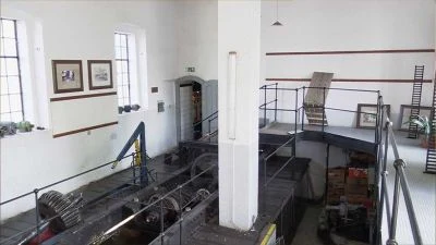 Vnitřní pohled na starou vodní elektrárnu s turbínami a chodbami.