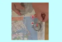 Kompas na mapě s rukama pro určení světových stran