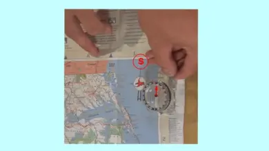 Kompas na mapě s rukama pro určení světových stran