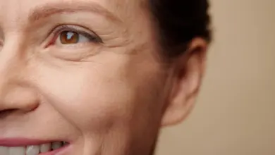 Žena se usmívá s vráskami mezi očima na tváři.