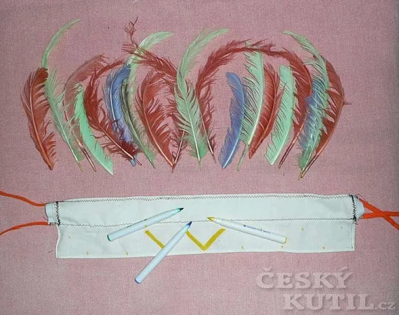 Květnaté peří a bílá čelenka s markerky na růžovém podkladu.