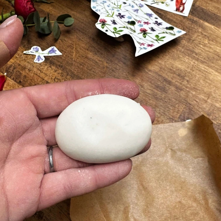 Ruka drží kuličku studeného porcelánu na dřevěném stole.